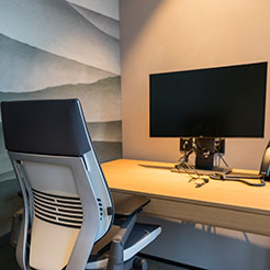 Schreibtisch mit Stuhl und Bildschirm in einem modernen kleinen Büro im Rotkreuz-Office